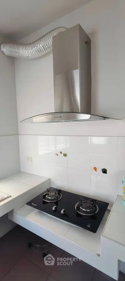 Modern kitchen with sleek gas stove and stainless steel range hood, perfect for culinary enthusiasts.