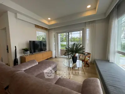 Spacious living room with modern decor and large windows offering garden views.