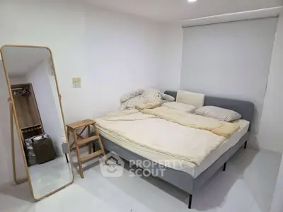 Cozy bedroom with modern bed, mirror, and minimalist decor in bright white space.
