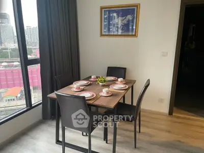 Modern dining area with city view, featuring elegant table setting and large window.