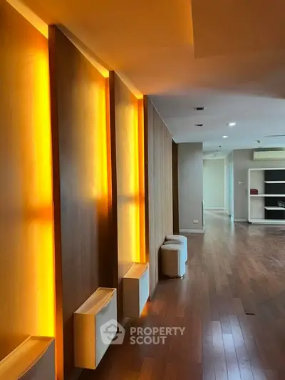 Modern interior with warm lighting and wooden flooring, featuring sleek design elements.