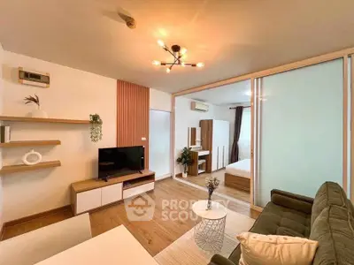 Modern living room with stylish decor and view into cozy bedroom through glass partition.