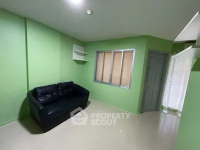 Cozy green living room with black leather sofa and modern shelving
