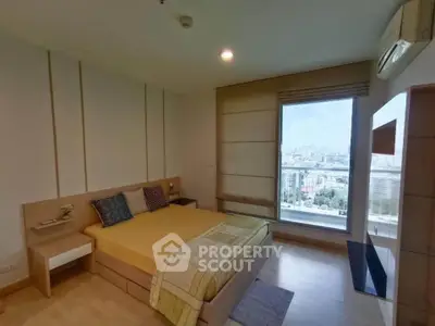 Modern bedroom with large window offering city view, featuring cozy bed and stylish decor.