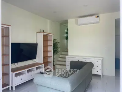 Modern living room with sleek furniture and wall-mounted TV, featuring a minimalist design and air conditioning.
