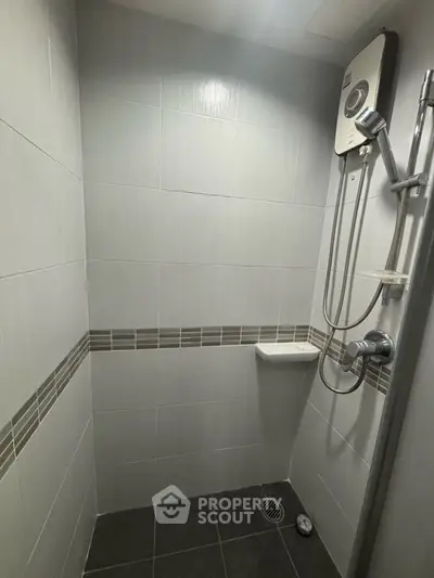 Modern bathroom with sleek tiles and shower heater, perfect for compact spaces.