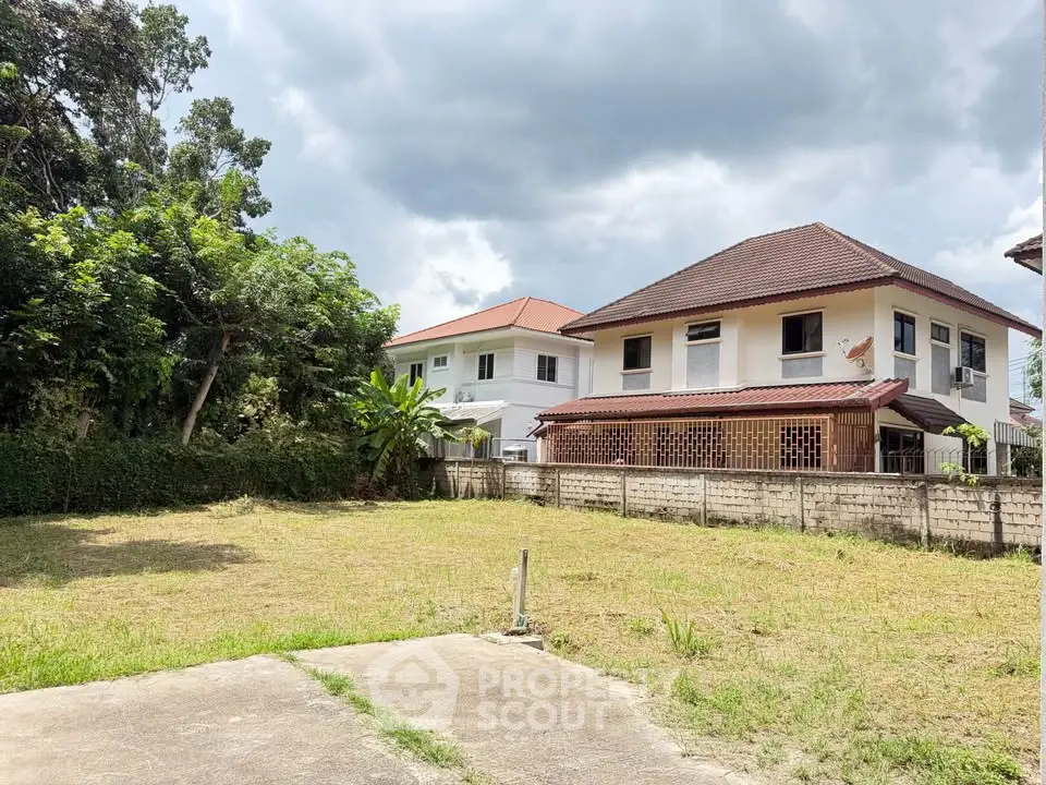 Spacious backyard with lush greenery and two-story house, perfect for family living.