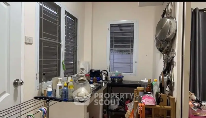 Compact kitchen with cluttered countertops and wall-mounted utensils.