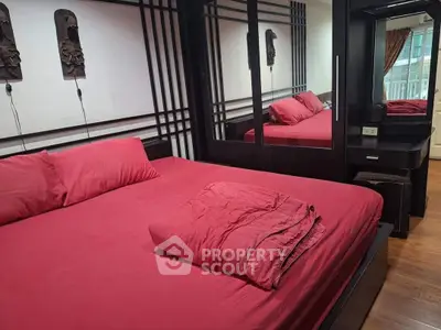 Luxurious bedroom with red bedding and mirrored wardrobe in modern apartment.