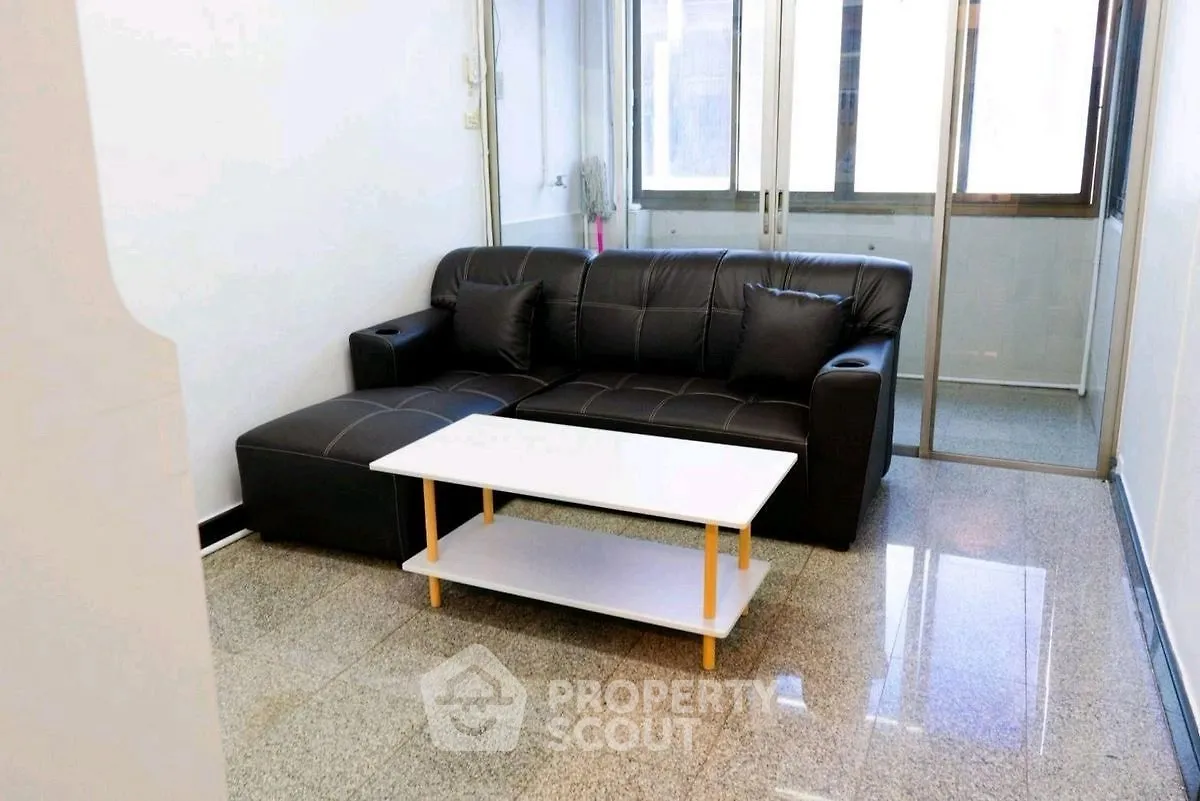 Modern living room with sleek black sofa and glass doors, perfect for urban living.
