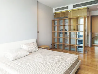 Spacious modern bedroom with wooden flooring and stylish shelving unit