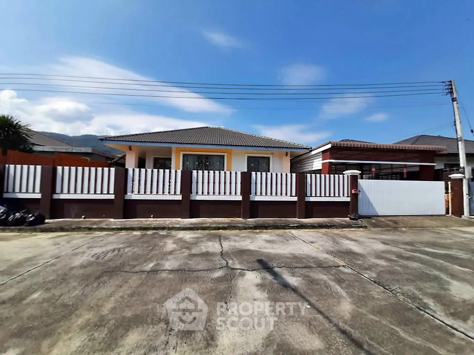 Charming single-story home with fenced yard and spacious driveway under clear blue skies.