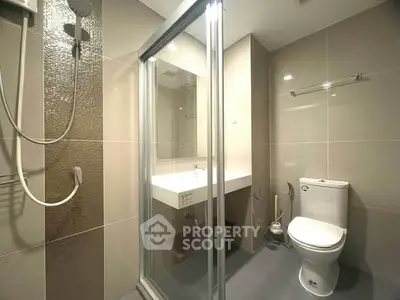 Modern bathroom with glass shower and sleek fixtures in contemporary apartment.