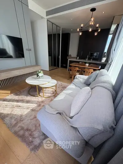 Modern living room with cozy sofa, stylish lighting, and open kitchen layout
