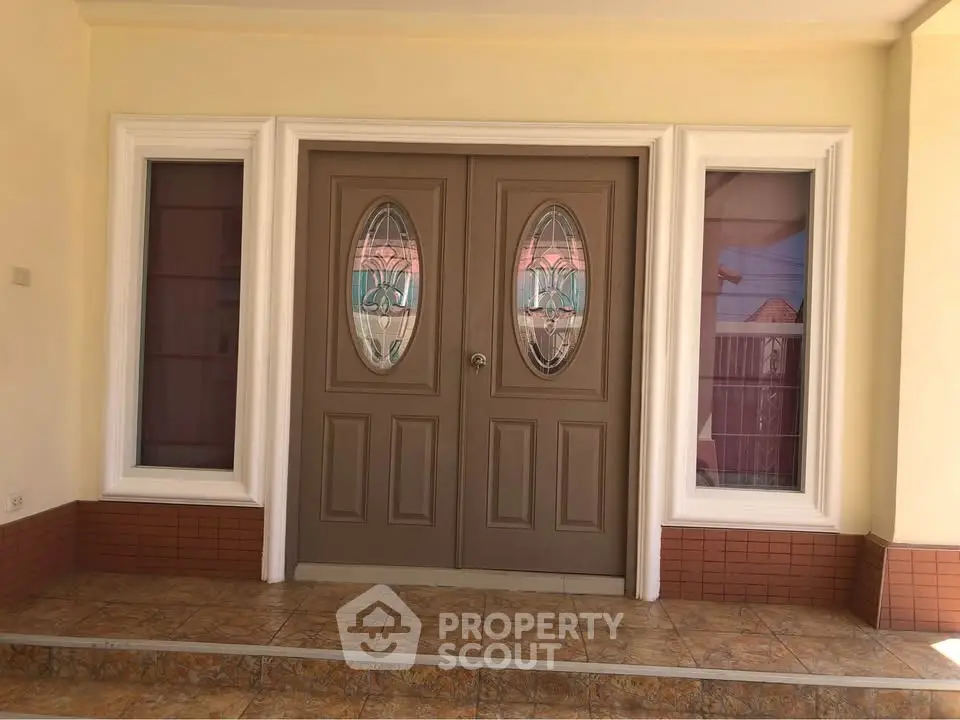 Elegant double door entrance with decorative glass panels and tiled steps.