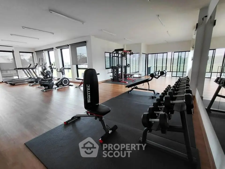 Spacious modern gym with state-of-the-art equipment and large windows for natural light.