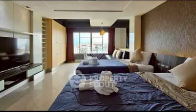 Spacious bedroom with modern decor and large windows offering city views.