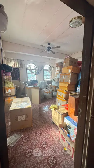 Spacious storage room filled with boxes and natural light from large windows.