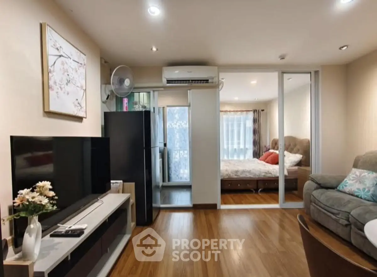 Modern living room with TV, sofa, and view into cozy bedroom