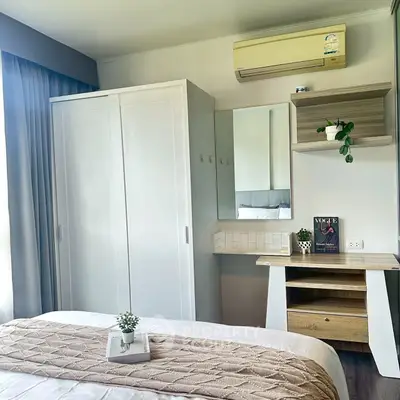 Cozy bedroom with modern decor and natural light, featuring a wardrobe and stylish desk.