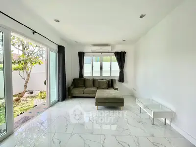 Bright living room with modern sofa and garden view through large windows