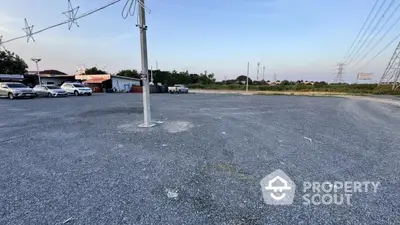 Spacious gravel parking lot with multiple cars and open sky view