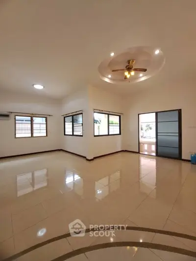 Spacious living room with ceiling fan and large windows in modern home