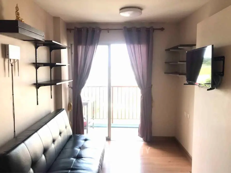 Modern living room with balcony access, featuring sleek leather sofa and wall-mounted TV for stylish comfort.