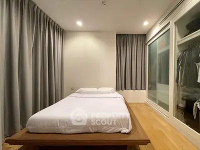 Spacious bedroom with modern design and ample closet space, featuring elegant curtains and wooden flooring.