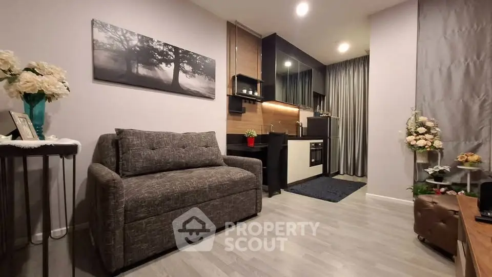 Modern living room with sleek kitchen, stylish decor, and cozy seating area.