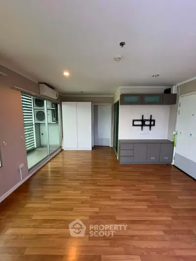Spacious living room with wooden flooring and balcony access in modern apartment.