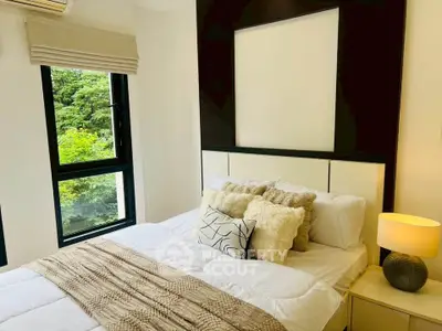 Cozy bedroom with modern decor and lush green view from window.