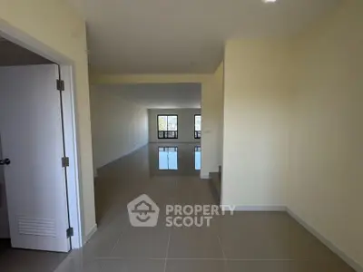 Spacious open-plan living area with glossy tiled floors and large windows for natural light.