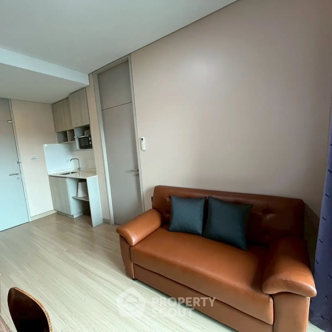 Modern living room with leather sofa and compact kitchen area