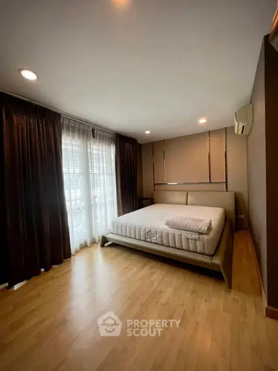 Spacious bedroom with large window and modern decor in a stylish apartment.