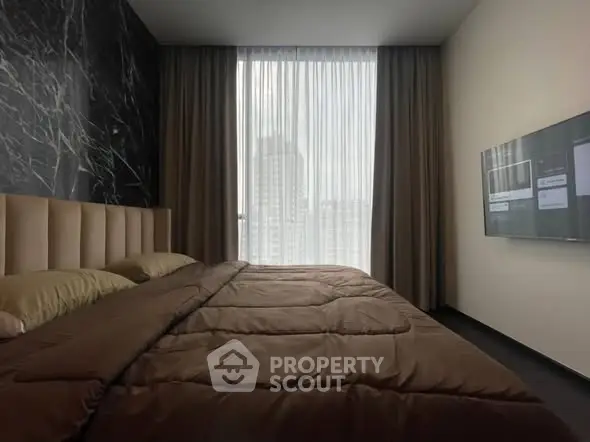 Luxurious bedroom with modern decor and city view, featuring a wall-mounted TV and elegant curtains.