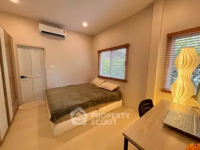 Cozy bedroom with modern decor and natural light, featuring a comfortable bed and workspace.