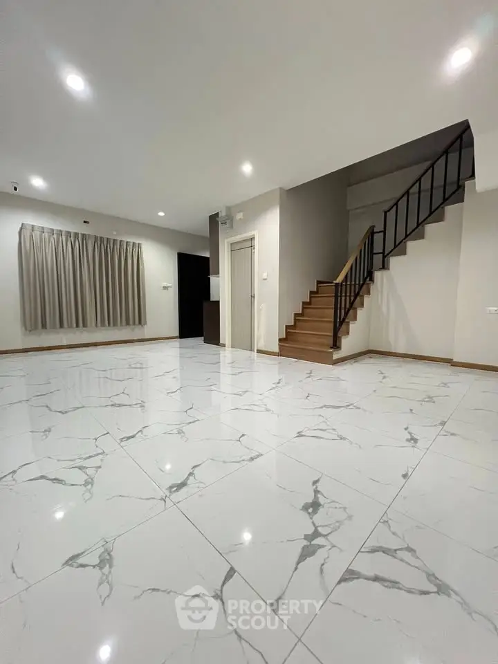 Spacious modern living room with elegant marble flooring and staircase, perfect for stylish living.