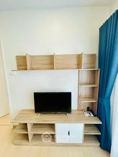 Modern living room with stylish wooden TV stand and shelves, complemented by elegant blue curtains.