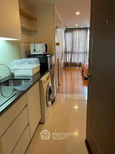 Modern apartment interior with kitchen and living area, featuring washing machine and sleek design.