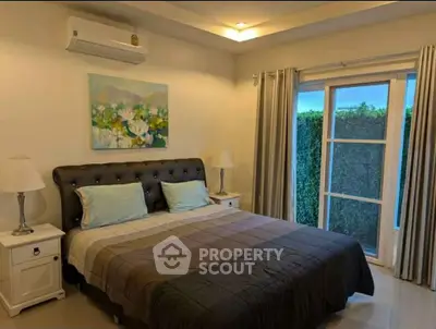 Cozy bedroom with large bed, elegant decor, and garden view.