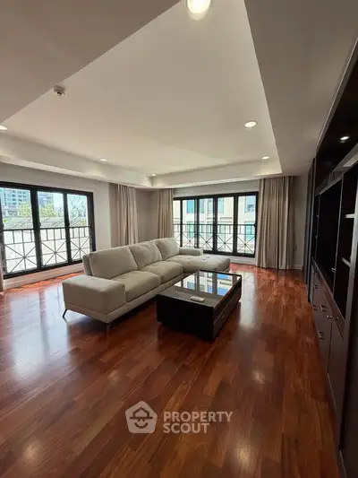 Spacious living room with elegant hardwood floors and large windows offering abundant natural light.