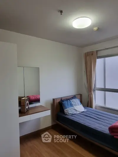Cozy bedroom with single bed, large window, and built-in vanity in modern apartment.