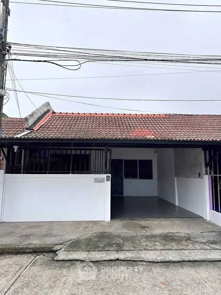 Charming single-story house with tiled roof and gated driveway, perfect for cozy living.