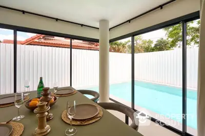 Modern dining area with pool view, featuring elegant table setting and large windows.