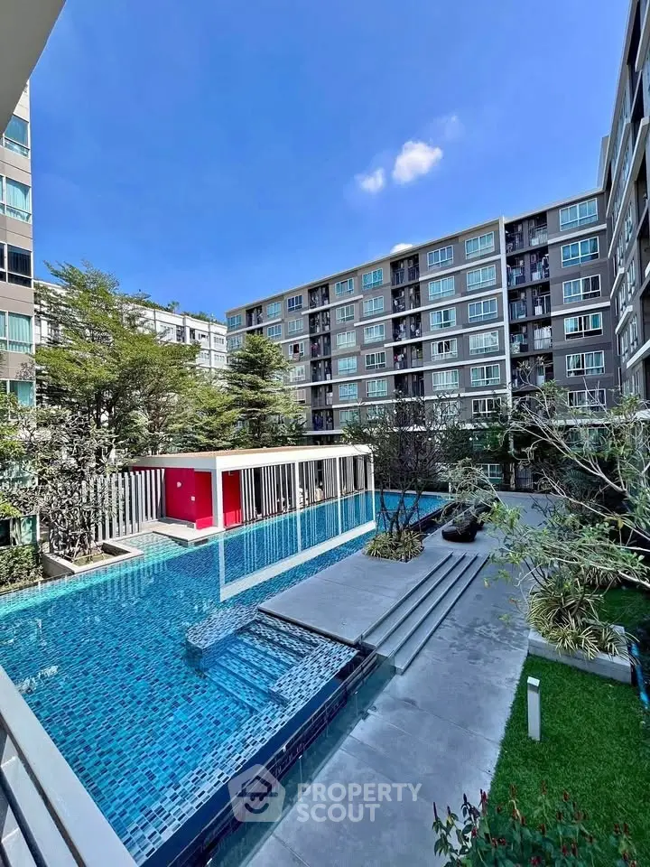 Modern apartment complex with stunning pool and lush garden view.