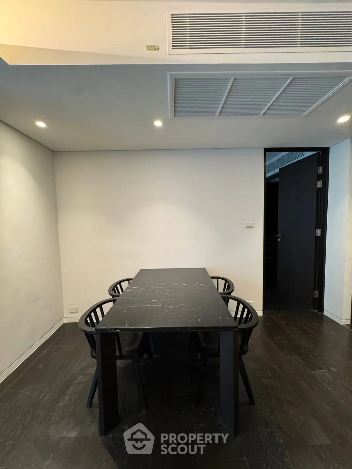 Modern minimalist dining area with sleek black table and chairs, perfect for contemporary living.