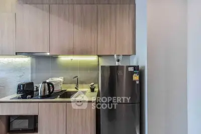 Modern kitchen with sleek appliances and wooden cabinetry in a stylish apartment.