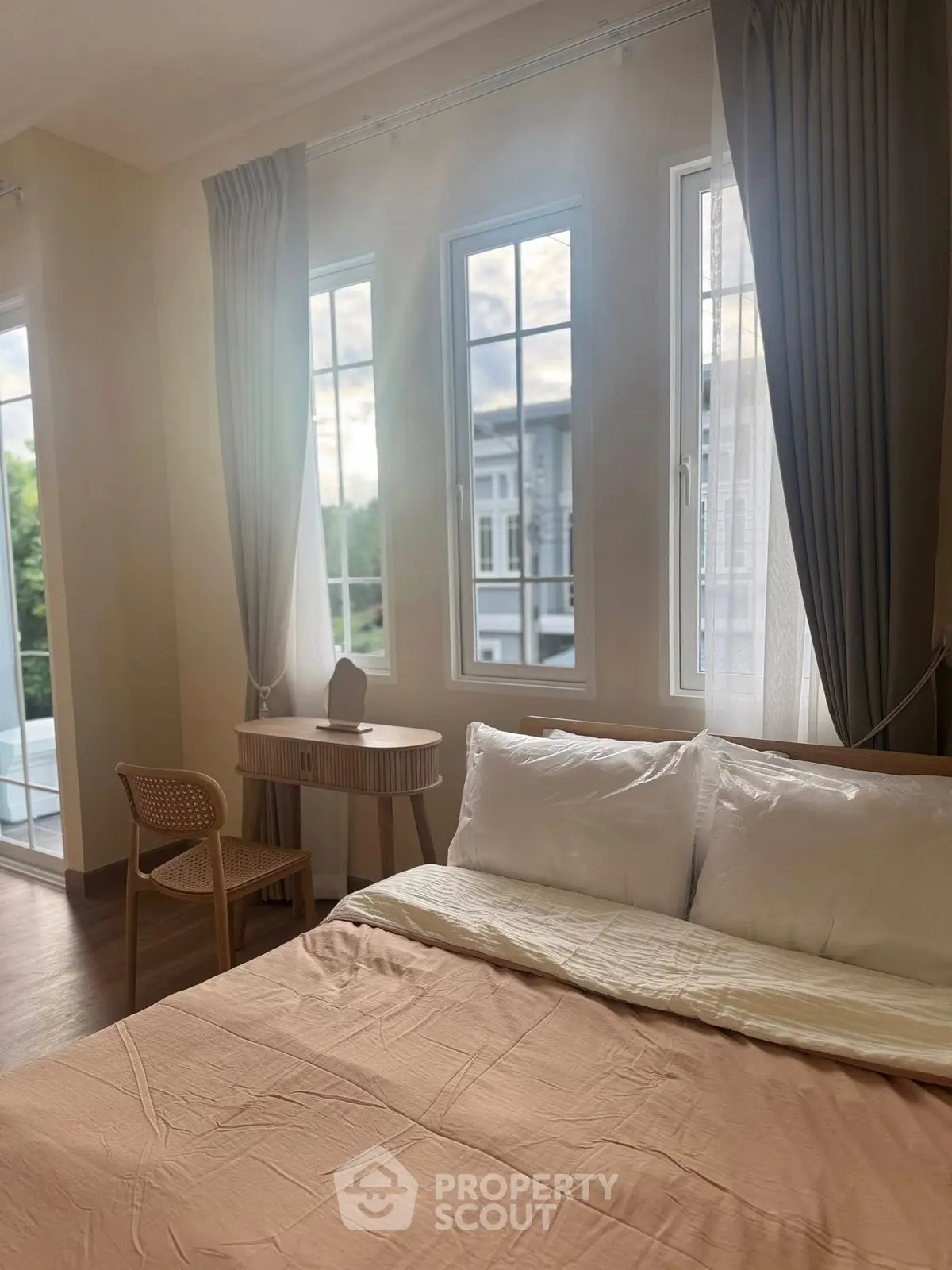 Cozy bedroom with large windows and elegant decor, offering a serene view.