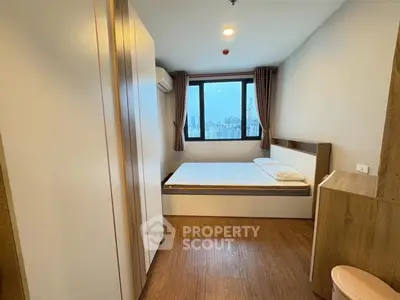 Modern bedroom with city view, wooden flooring, and stylish furnishings in a high-rise apartment.